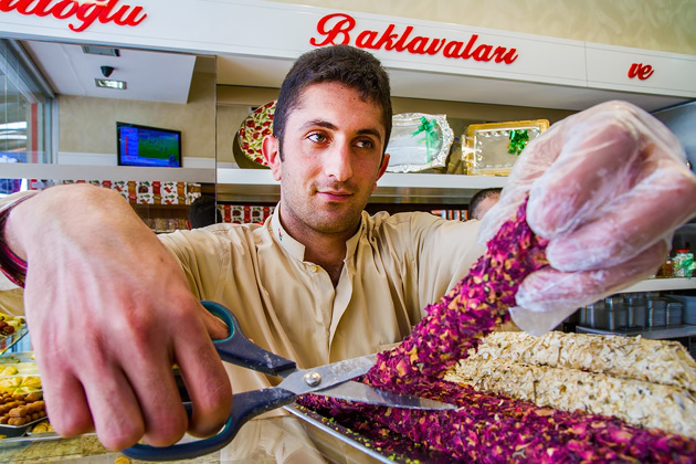 Man is cutting turkish delight with scissors