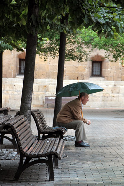 Man with umbrella sitting on a bench in Oviedo Asturias